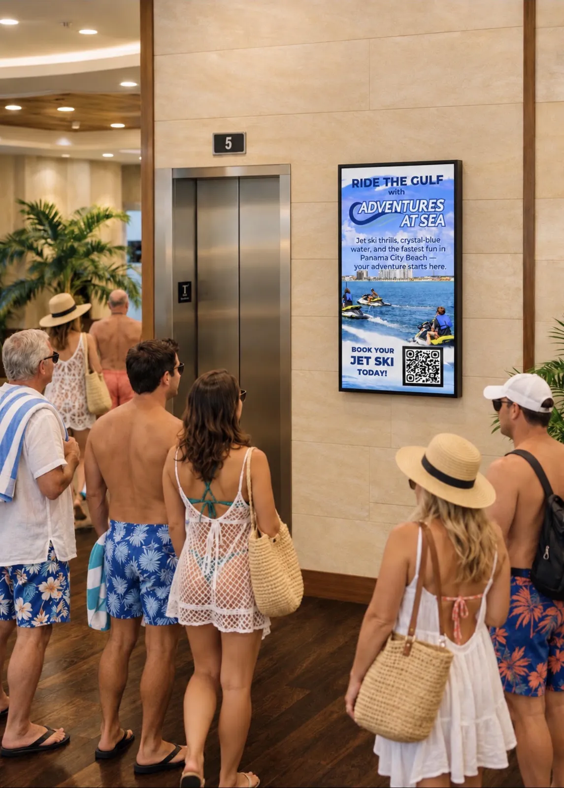 Beachgoers waiting for a hotel elevator beside a CDS digital display running a jet ski ad